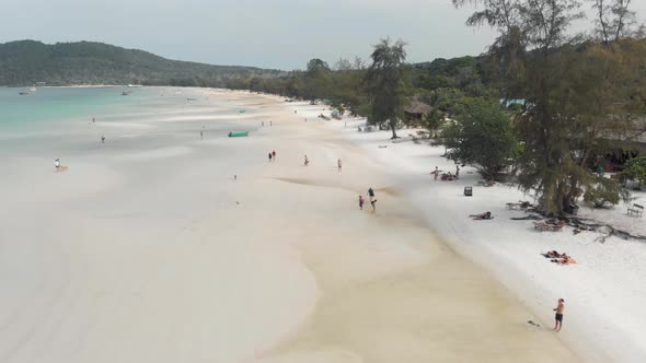 Fly over people strolling along white sand beach of Koh Rong Samloem. Tropical holidays, Cambodia