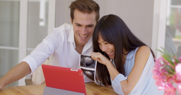 Happy Couple Showing Off Ultrasound Pictures