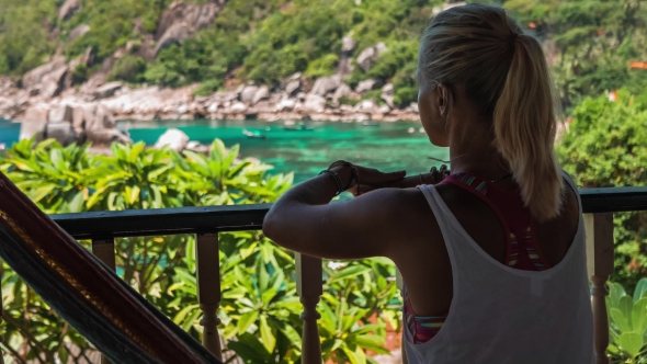 Girl Sitting in Hammock on an Terrace and Showing with Her Hand the Beautiful Tanote Bay, Koh Tao
