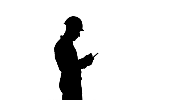 Silhouette Contractor Engineer in Hardhat Inspecting Construction Site Holding Digital Tablet alt