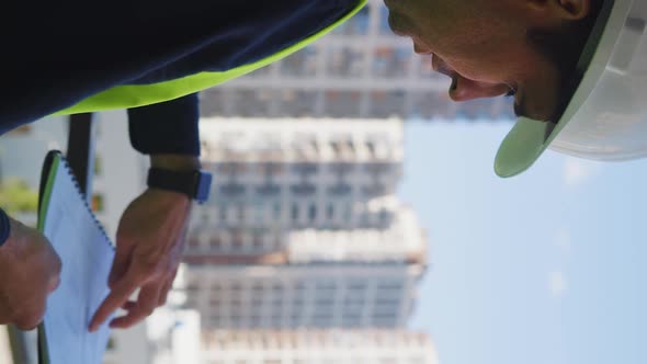 Vertical Screen Engineers Discussing Blueprint on Construction Site