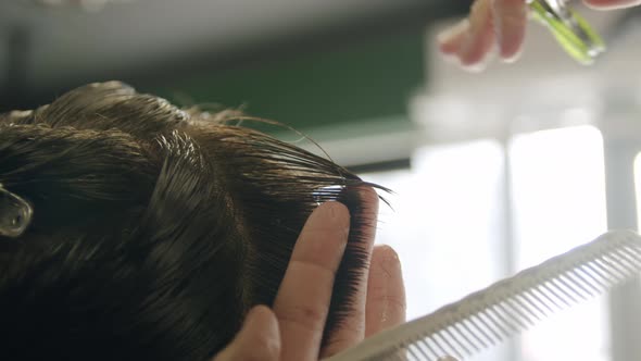 Close Up Shot of Barber Cuts the Young Man's Hair with Scissors