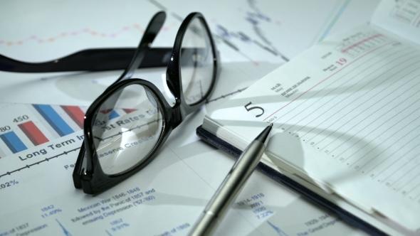 Spinning Office Desk with Business Graphics, Glasses, Pen and Notebook