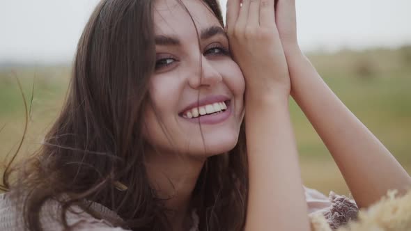 Beautiful Close Portrait of Young Brunette with Blowing Hair Smiling at Camera