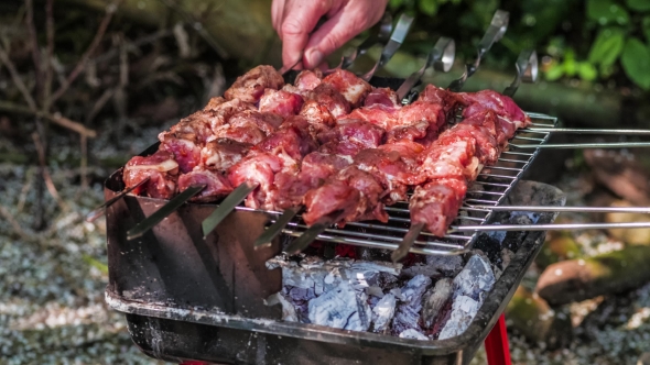 Raw Meat Marinated in Tomato and Onion on the Skewers on the Grill. Turning Servings of Barbecue