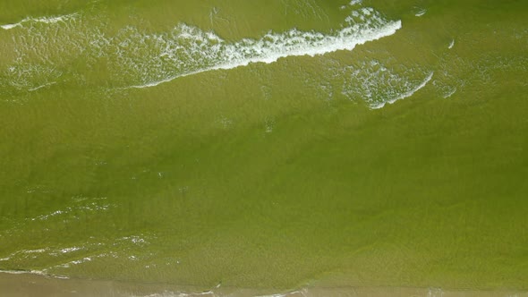 Flying over green water of Baltic sea daytime in autumn, foamy sea waves, simplistic background, tem