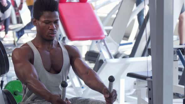 Ripped Young African Man Working Out on Low Row Cable Gym Machine