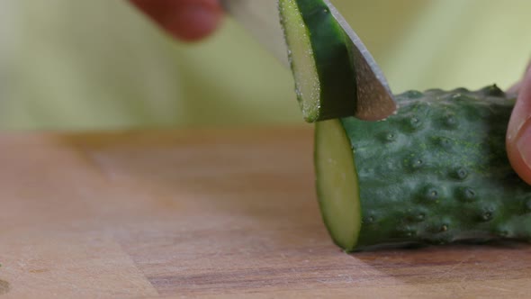 Hand Cuts With Knife Cucumber On the Table In Kitchen