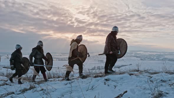 Group of Medieval Vikings with Arms and Shields Going on The Winter Meadow