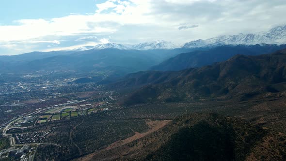 Aerial orbit of the foothills at Morro Las Papas, Las Condes, Santiago, Chile. Snowy Andes mountain