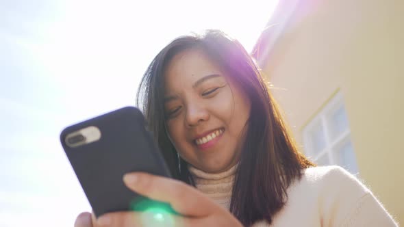 Close up of Asian woman happy standing and using her smart phone