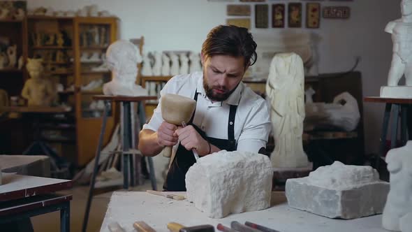Master Sitting in the Craft Studio and Knocking off Limestone the Future Sculpture Using Hammer