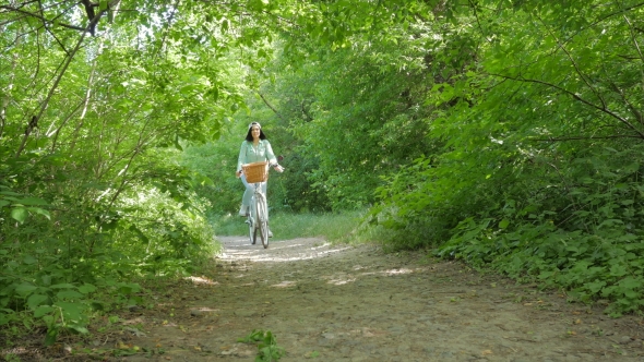 Young Beautiful Woman Wearing Casual Clothing Jeans, Cap and Backpack Riding a Vintage White Bicycle