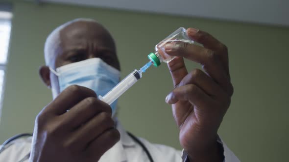 African american male doctor wearing face mask preparing injection