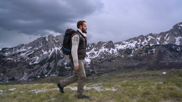 Hiker Going Along Grassy Slope