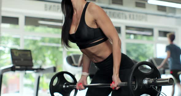 Young Woman Lifting Barbell in Gym