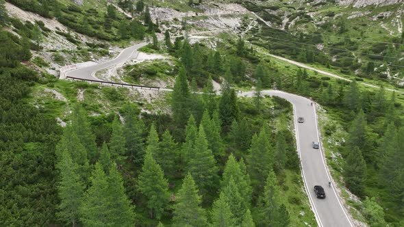 Flying above motorbikers and cyclists riding down a winding mountain road in the Dolomites