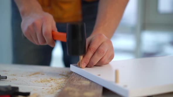 Man Clogging Wooden Dowel Using Mallet