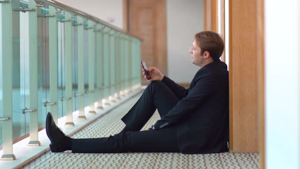 Businessman using phone. Corridor.
