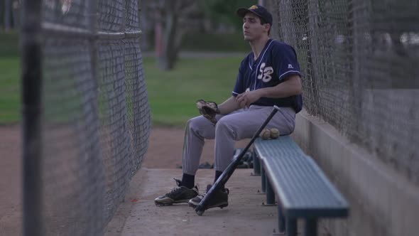 A baseball player resting on the bench.