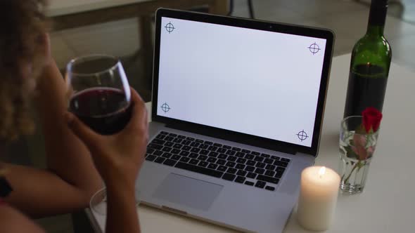 Mixed race woman having a romantic dinner on video chat using laptop with copy space