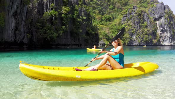 Woman Paddling a Kayak in the Island Lagoon Between Mountains. Kayaking in El Nido, Palawan