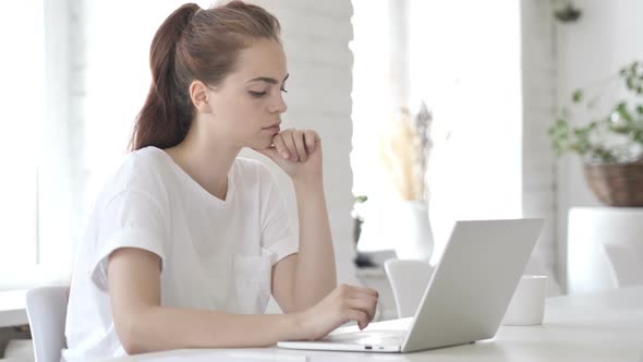 Pensive Young Woman Thinking and Working on Laptop