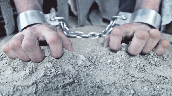a Prisoner in Chains on His Knees Touching the Dusty Ground