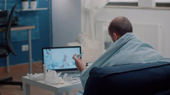 Man with Sickness Looking at Thermometer on Video Call