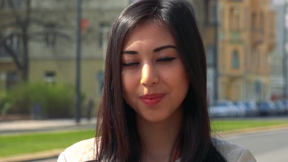 A Young Asian Woman Smiles at the Camera in an Urban Area