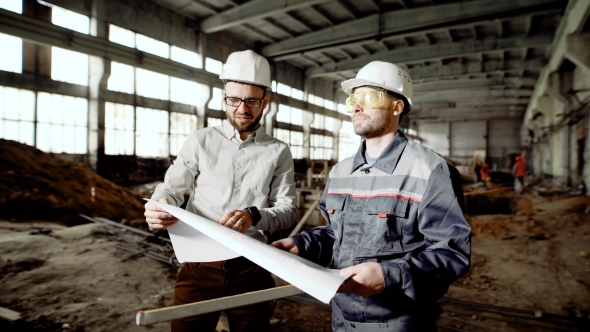 Foreman and Chief Engineer at the Construction Site of the Factory. The Engineer Checks the Drawing