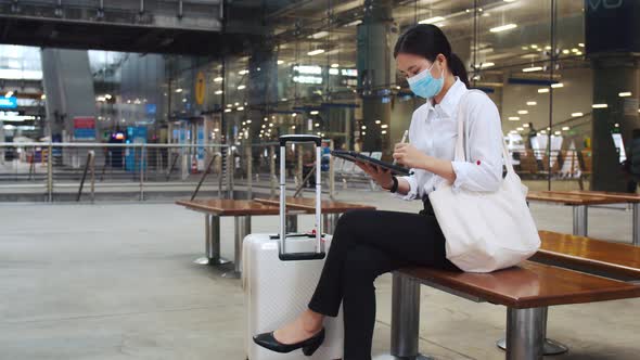 Attractive businesswoman wearing a surgical mask working on a tablet check email.