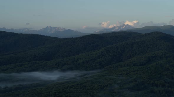 Aerial Drone Panning Shot of a Lake Surrounded By Mountains and Small Camping Tents on One of the