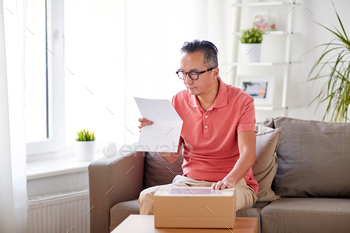  man with parcel box reading invoice at home