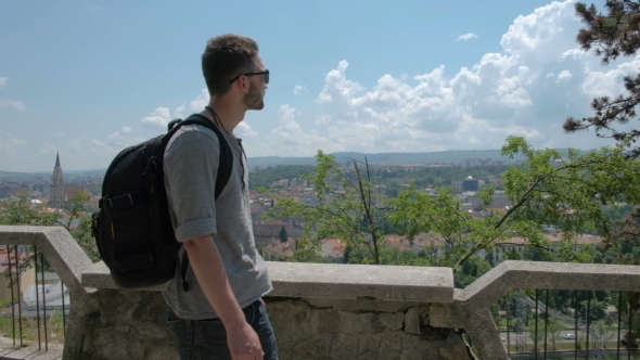 Man Traveler with Backpack Explores the City Looking at the Panoramic View of the City and the Coast