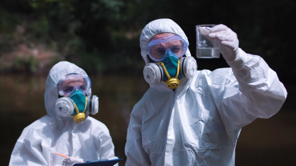 Two Ecological Workers in Biohazard Suits Sampling Water