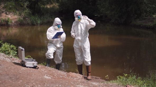 Two Scientists Taking Water Samples From a River