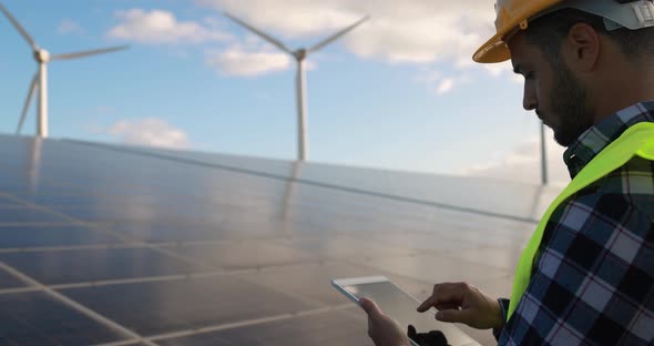 Young man working with digital tablet inside wind farm - Ecology concept