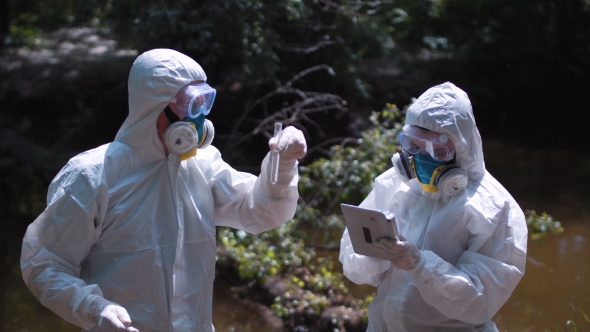 Two Ecological Workers in Biohazard Suits Sampling Water
