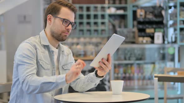 Successful Man Celebrating on Tablet in Cafe