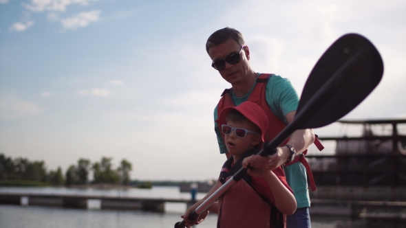 The Father Teaches the Son How To Row in a Kayak