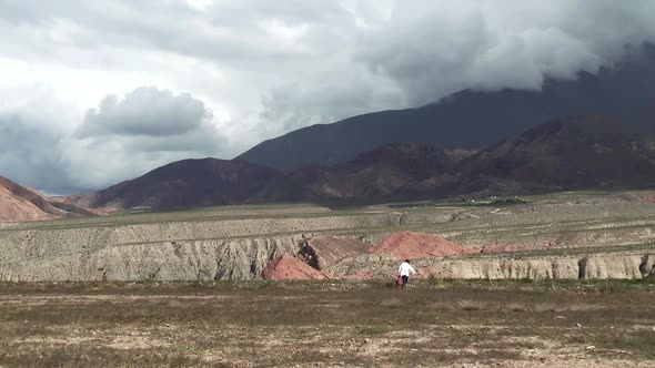 Child School Boy with Backpack walking on a Little Path in Mountains.