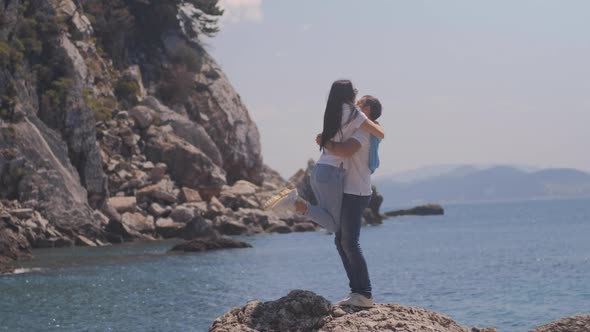 Romantic couple stand and embrace near the sea. Man and woman with black hair spend vacation