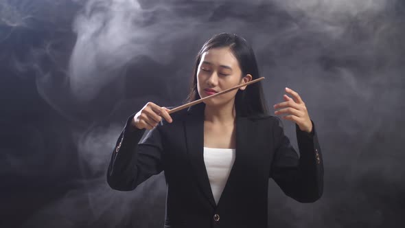 Asian Conductor Woman Holding A Baton And Showing Gesture Quickly In The Black Studio With Fog