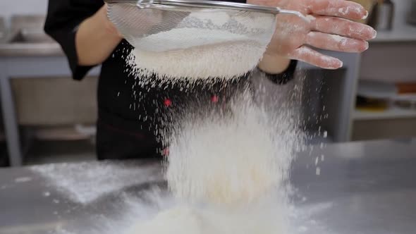Closeup of a Female Cook Sifting Flour Through a Sieve in the Kitchen