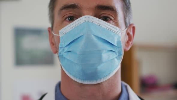 Portrait of caucasian teacher puttin on face mask while in classroom