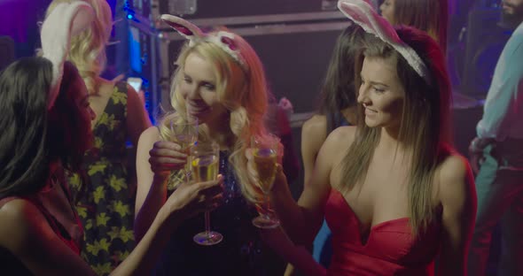 Female friends having fun with champagne and talking in nightclub