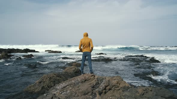 Tourist Man in Yellow Sweatshirt Walks on Volcanic Beach in North of Canary Island Tenerife