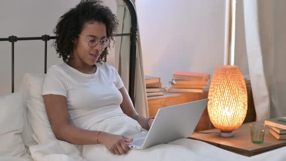 Video Call on Laptop By Young African Woman in Bed 