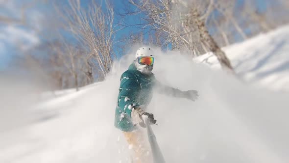 Concept of Extreme, Sport, Winter, Freeride, Snowboarding. Man Riding on Snowboard with Selfie Stick